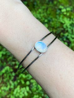 This classic bracelet is set in the center with a rainbow moonstone cabochon, with an elegant & sleek split style cuff. Adjustable to fit most wrists by gently opening and closing around the wrist. Sterling silver. Stone is approx. 1/2" long. Elegant Oval Cabochon Cuff Bracelet, Adjustable Oval Modern Cuff Bracelet, Modern Adjustable Cabochon Jewelry, Adjustable Elegant Moonstone Ring Oval Cabochon, Modern Silver Bangle With Gemstone, Modern Silver Gemstone Bangle, Elegant Moonstone Cuff Bangle Bracelet, Elegant Moonstone Bangle Cuff Bracelet, Modern Adjustable Oval Bangle