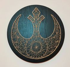 a wooden wall hanging with a star wars symbol on it's side and string work in the shape of a crescent