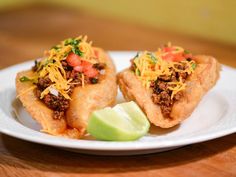 two taco shells on a white plate with lime wedge