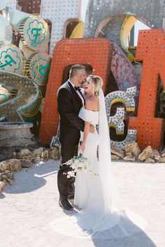 This lovely couple glows amidst vintage neon signs, showcasing a simple wedding dress and enchanting wedding hairstyles. Their intimate embrace, the bride's sparkling veil, and whimsical bouquet create a charming scene of affection. 💖✨ Don't miss out on more dreamy wedding inspiration! Sparkling Veil, Whimsical Bouquet, Sparkle Veil, All Inclusive Wedding Packages, Enchanting Wedding, Timeless Wedding Dress, Vintage Neon Signs