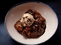 a white bowl filled with ice cream and chocolate dessert on top of a black table