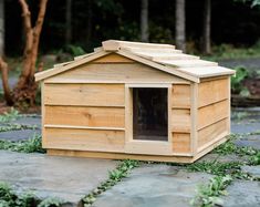 a wooden dog house sitting on top of a stone floor next to a wooded area