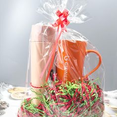 an orange coffee mug sitting on top of a table next to a plastic bag with red and green streamers