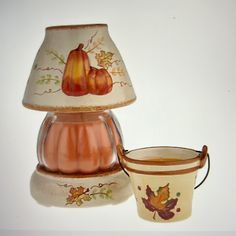 a lamp shade with two pumpkins on it next to a small potted plant