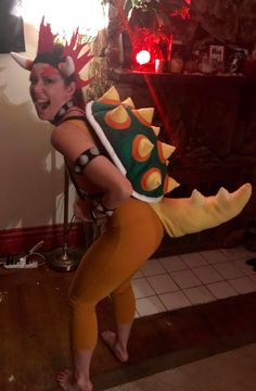 a woman dressed as a dragon is standing on one leg and has her hands in the air