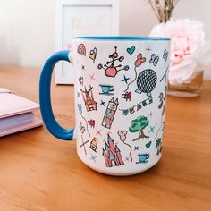 a blue and white coffee mug sitting on top of a wooden table next to a notebook