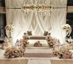 an elegant wedding setup with flowers and candles on the floor, along with white drapes