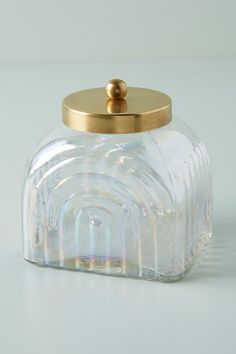 a glass jar with a gold lid on a white surface, the container is empty