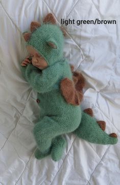 a stuffed animal that is laying down on a white sheet with the caption light green / brown