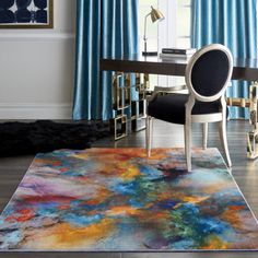 an area rug with a chair and desk in front of blue curtained window curtains