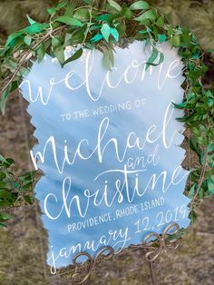 a welcome sign with greenery around it