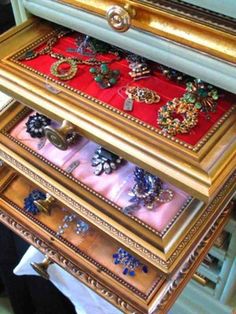 an old dresser with many different jewelry on it's drawers and gold trimmings