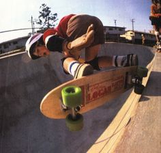 a man riding a skateboard up the side of a cement ramp at a skate park