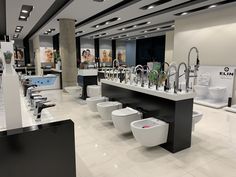 a bathroom with several toilets and sinks in it's center area, all decorated in black and white