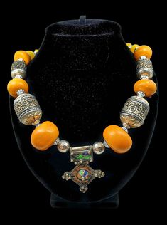 Add a Touch of Elegance to Your Wardrobe with This One-of-a-Kind Enamel Vintage Necklace! This beautiful necklace is handcrafted from local stainless carved metal and fossilized tree sap resin and is sure to add a touch of elegance to any outfit. The necklace is made in the Moroccan Berber Amazigh tradition and features intricate details and bright colors. It is the perfect choice for a woman who wants to add a touch of sophistication to her look. Features: Handcrafted from local stainless carve Traditional Amber Jewelry With Colorful Beads, Traditional Orange Necklaces For Festivals, Bohemian Jewelry With Polished Beads For Traditional Ceremonies, Traditional Orange Jewelry For Ceremonies, Traditional Gold Bead Necklaces For Ceremonies, Traditional Gold Beaded Necklaces For Ceremonies, Spiritual Beaded Jewelry For Traditional Ceremonies, Bohemian Orange Necklace For Wedding, Traditional Orange Beaded Necklaces For Festivals