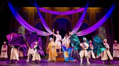 a group of people standing on top of a stage in front of purple drapes