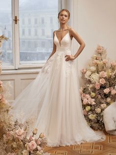 a woman standing in front of a window wearing a wedding dress