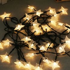 a bunch of white stars are on the ground with some string lights around them and one light is turned on