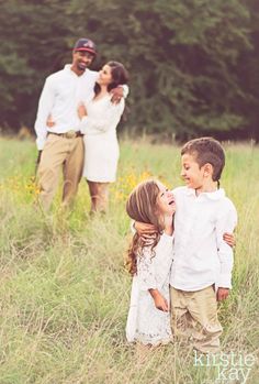 a family standing in tall grass with their arms around each other