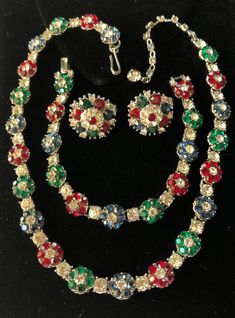 "Here is a very lovely vintage necklace, bracelet and earrings set designed by Trifari. This jewelry is beautifully fashioned in a floral pattern with glittering rhinestones in jewel tones of emerald green, sapphire blue, ruby red and brilliantly clear tones. The stone setting is in silver tone metal. The necklace has a hook and adjustable extension strand for a custom fit while the bracelet has a flip over clasp for closure. The earrings are in a clip-on style. The necklace measures 16\" from e Rhinestone Costumes, Vintage Jewelry Sets, Trifari Jewelry, Vintage Trifari, Vintage Style Jewellery, Pretty Necklaces, Pretty Bracelets, Green Sapphire, Red Blue Green