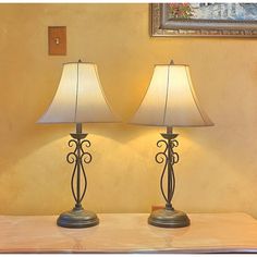 two lamps sitting on top of a table next to each other in front of a painting