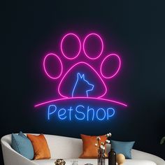 a neon sign that says petshop with a dog's paw on it in front of a couch