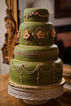 a three tiered green cake sitting on top of a table next to a mirror