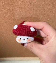 a hand is holding a small crocheted mushroom