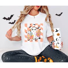 a woman sitting on the floor holding a cup and wearing a halloween t - shirt