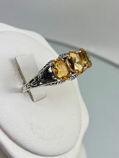 Natural Yellow Citrine 3Gem RingSmall 3Stone Design#D41 The Small 3Stone design #D41 is an elegant and exquisite filigree ring, made from sterling silver and inspired by Art Deco style designs. This high-quality cocktail ring is the perfect balance of classic beauty, vintage elegance, and modern grace. The triple stones of this ring – two 7x5mm side stones and one 8x6mm centerpiece – are expertly cut; they sparkle in the light, highly enhancing its glamour while also guaranteeing it won't go unn Formal Three Stone Yellow Jewelry, Formal Yellow Three Stone Jewelry, Yellow Citrine Topaz Ring With Accent Stones, Yellow Citrine Rings With Accent Stones, Yellow Topaz Ring With Citrine Accent Stones, Yellow Topaz Ring As A Gift, Yellow Three Stone Rings For Anniversary, Yellow Three Stone Anniversary Rings, Yellow Three Stone Ring For Gift