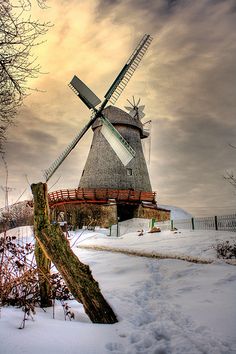 a snow covered field with a windmill in the background