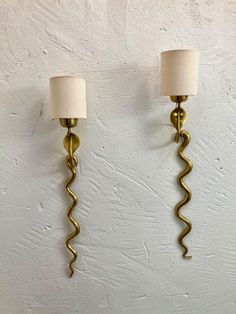 two wall sconces with lamps attached to them against a white wall in a room