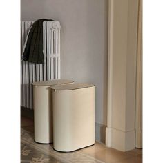 two white trash cans sitting next to each other in front of a radiator