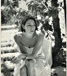 black and white photograph of a woman sitting on a bench in front of a tree