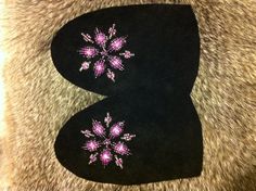 two black beanies with pink and white snowflakes on them sitting on a furry surface