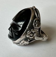 an amazing old ring, arts and crafts style with a Mexican mask stone, onyx, i think.  this is an old piece in very good condition,  stone has a little wear on edges and on tip of nose, but looks very good, as does the silver.  beautiful piece, unmarked. size:  measures a 5, fits larger.  i can barely get it over my size 5.5 knuckle, but once over the knuckle it fits fine.  so, depending on the size of your knuckles, i'd say 5.25 or 5.5 Height of face:  1" height off finger:  7/16" width of inner Mexican Mask, Arts And Crafts Style, Nouveau Jewelry, Old Rings, Art Nouveau Jewelry, Black Stone, Stone Art, Rings Statement, Statement Rings