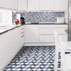 a kitchen with blue and white tiles on the floor, counter tops, cabinets and chairs