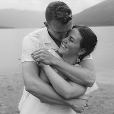 a man and woman hugging each other on the beach