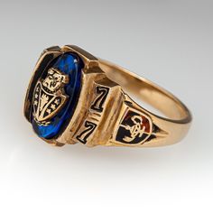 This vintage class ring features an oval blue stone accent with a bulldog head at its center. The ring is from 1977 and is crafted of 10k yellow gold. We love the natural patina left on the gold. Vintage Yellow Gold Sapphire Ring Collectible, Vintage Oval Sapphire Ring With Polished Finish, Collectible Classic 14k Gold Sapphire Ring, Vintage 14k Stamped Sapphire Ring Collectible, Classic 14k Gold Sapphire Collectible Ring, Vintage Gold Sapphire Oval Ring, Gold Oval Sapphire Ring For Collectors, Vintage Blue Signet Ring For Formal Occasions, Vintage Gold Sapphire Ring With Polished Finish