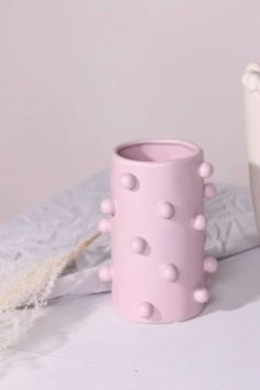 two pink vases sitting on top of a white table next to each other with holes in them