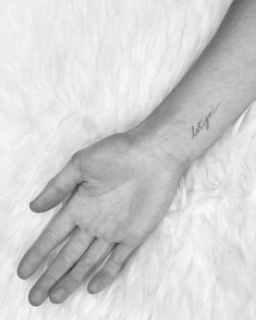 a woman's hand with a small tattoo on it and the word love written in cursive writing