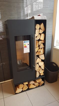 a stack of firewood sitting in front of a window next to a trash can