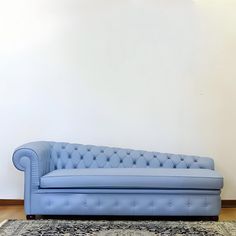 a blue couch sitting on top of a wooden floor next to a rug and wall