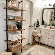 a bathroom with white walls and wooden shelves filled with towels, baskets and other items