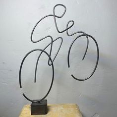 a metal bicycle sculpture sitting on top of a yellow table next to a white wall