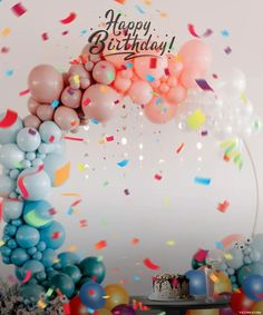 a birthday cake surrounded by balloons and confetti