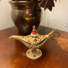 an ornately decorated teapot sits on a table next to a potted plant