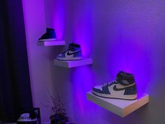 three shelves with shoes on them in front of a purple light