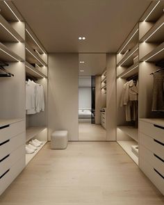 a walk in closet with white drawers and lights