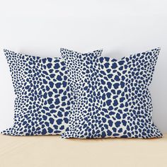 two blue and white pillows sitting on top of a bed